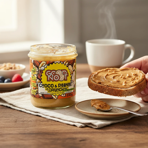 Słoik kremu orzechowo-czekoladowego Guiltfree Good Noot Choco & Peanoot Crunchy obok kromki chleba z masłem orzechowym.